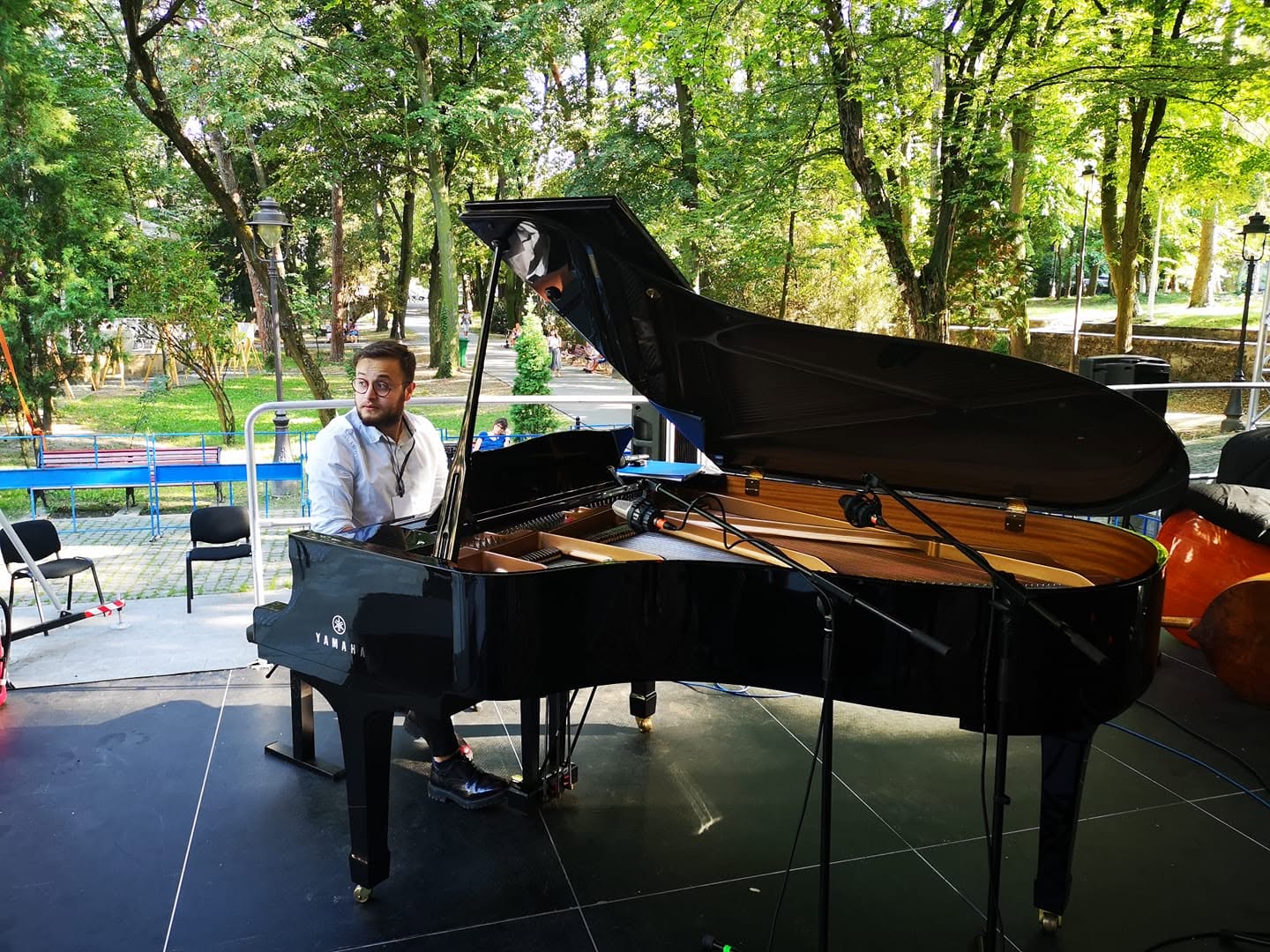 Mihai Paun cântând la pian cu coadă, pe scenă în parc